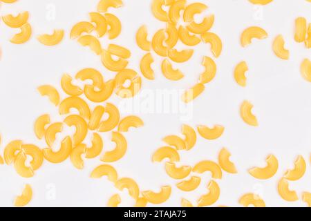 Verstreute ungekochte Chifferi Rigati Pasta auf weißem Hintergrund. Fett und ungesunde Lebensmittel. Klassische Trockene Makkaroni-Textur. Italienische Kultur und Küche. Rohe Pasta Stockfoto