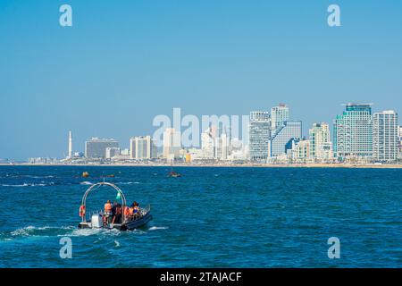 Blick auf die Stadt Tel Aviv vom Meer aus. Ein Ausflugsboot mit Touristen segelt im Mittelmeer Stockfoto