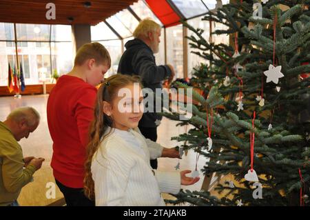 Berlin, Deutschland. Dezember 2023. Schüler aus Selb, Bayern, schmücken den Weihnachtsbaum in der tschechischen Botschaft in Berlin, die am 1. November 2023 von Bundesabgeordneten Jorg Nürnberger (nicht gesehen) im Rahmen der Förderung der deutsch-tschechischen Grenzbeziehungen initiiert wurde. Quelle: Zapotocky Ales/CTK Photo/Alamy Live News Stockfoto