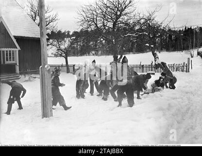 Eine Schulklasse hat eine Pause und wirft sich vor der ländlichen Dorfschule auf der Insel Ornö im südlichen Stockholmer Archipel Schneebälle aufeinander. Schweden Februar 1940. Kristoffersson Ref. 61-4 Stockfoto