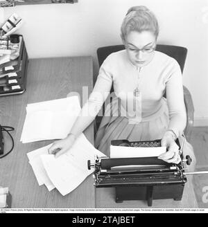 Büromädchen in den 1950ern Eine Frau sitzt an einem Schreibtisch und tippt auf ihre Schreibmaschine. 1957. Stockfoto