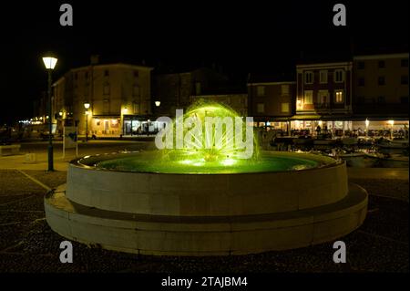 Cres, Kroatien - 8. April 2023: Detail eines Brunnens auf dem Hauptplatz in der Nähe des Hafens in Cres mit farbigen Lichtern Stockfoto