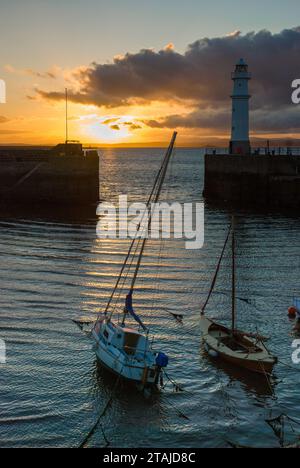 Boote bei Sonnenuntergang im Hafen von newhaven in Edinburgh mit Leuchtturm an der Ufermauer Stockfoto