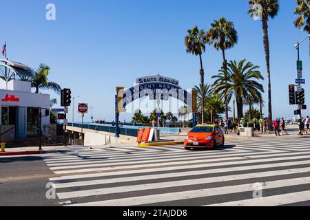 Orange und Gelb, Toyota Prius Taxifahrt vom Santa Monica Pier auf die Ocean Avenue unter dem Pier Arch., Kalifornien, Vereinigte Staaten von amerika. Stockfoto