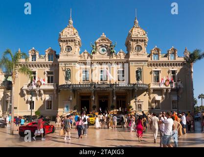 Teure Autos, Leute, die sie sehen und das Äußere von Monte Carlo / Monte-Carlo Casino, Monaco. Sonniger Sommertag mit Sonne und blauem Himmel. (135) Stockfoto