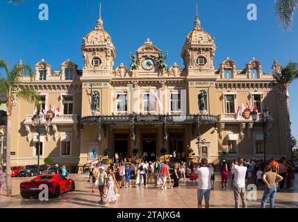 Teure Autos, Leute, die sie sehen und das Äußere von Monte Carlo / Monte-Carlo Casino, Monaco. Sonniger Sommertag mit Sonne und blauem Himmel. (135) Stockfoto