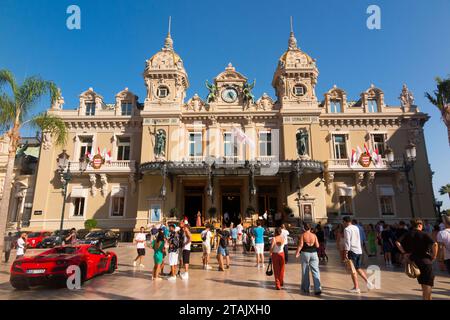 Teure Autos, Leute, die sie sehen und das Äußere von Monte Carlo / Monte-Carlo Casino, Monaco. Sonniger Sommertag mit Sonne und blauem Himmel. (135) Stockfoto