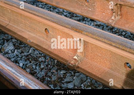 Verschweißte alte, rostete Eisenbahnschienen auf dem Kiesboden, Nahaufnahme Foto Stockfoto