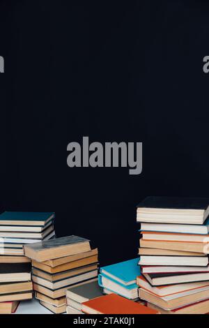 Viele Stapel alter Lehrbücher in einer Bibliothek mit schwarzem Hintergrund Stockfoto