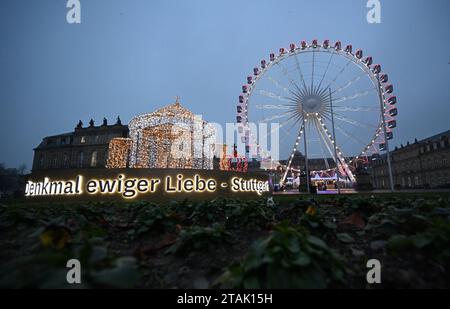 Stuttgart, Deutschland. Dezember 2023. Auf dem Stuttgarter Schlossplatz erstrahlt eine beleuchtete Skulptur der Grabkapelle. Ein Riesenrad auf der rechten Seite. Quelle: Bernd Weißbrod/dpa/Alamy Live News Stockfoto