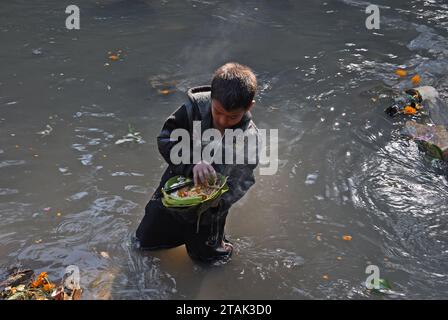 Ein Kind benutzt einen Magneten, um Münzen vom Grund des Flusses Bagmati zu sammeln. Das Bala Chaturdashi Festival ist eine Feier in Nepal, die jedes Jahr Ende November oder Anfang Dezember im Pashupatinath Tempel in der Nähe von Kathmandu stattfindet. Hindu-Pilger aus ganz Nepal und Indien versammeln sich am Pashupatinath-Tempel, der als der heiligste Tempel von Shiva (Pashupati) in Nepal gilt. Eine Nachtwache im Licht kleiner Dochtlampen markiert den Beginn von Bala Chaturdashi. Kathmandu, Nepal. Stockfoto