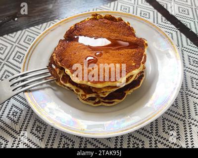 Hausgemachte Pfannkuchen übereinander gestapelt, mit etwas Ahornsirup darüber Stockfoto