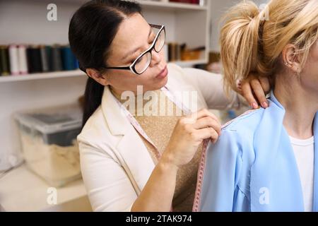 Erfahrene Näherin mit Maßband während der Montage Stockfoto