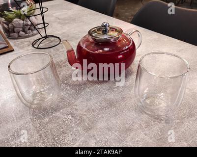 Ein Glaskessel mit Früchtetee und zwei Gläser daneben Stockfoto