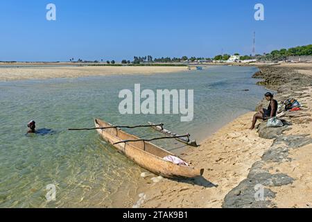 Einzel-Ausleger-Kanu und zwei einheimische madagassische Frauen am Strand im Küstenort Belo sur Mer, Bezirk Morondava, Region Menabe, Madagaskar Stockfoto
