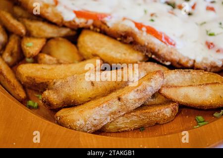 Gebackene Kartoffelecken mit Käse und Kräutern und Tomatensauce auf schwarzem Hintergrund - hausgemachte Bio-gemüsegarten vegan vegetarische Potato Wedges Snack Food Stockfoto
