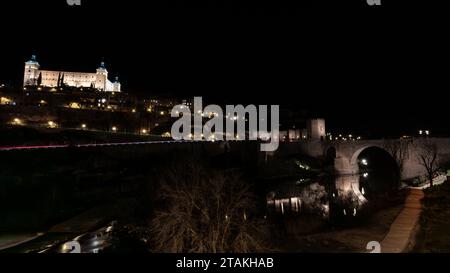 Lange Exposition der Alcantara-Brücke, einem historischen Bau über dem Tejo und dem Real Alcazar bei Nacht, in der Stadt Toledo, Spai Stockfoto