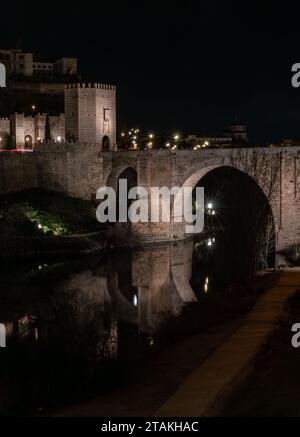 Alcantara-Brücke mit dem Turm am Eingang der Stadt und seiner Reflexion im Fluss Tejo mitten in der Nacht. Historisches Bauwerk Stockfoto