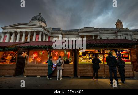 London, Großbritannien - 20. November 2023: Trafalgar Square Christmas Market, London. Die Leute an den Marktständen mit der National Gallery am Trafalgar Square dahinter. Stockfoto