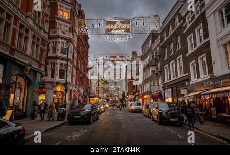 London, Großbritannien - 20. November 2023: St Martin's Lane im Zentrum von London. Menschen, die über dem Bürgersteig mit Weihnachtslichtern laufen. Stockfoto