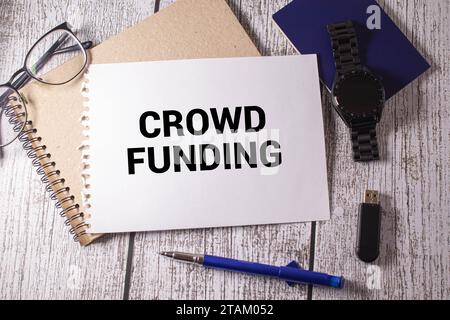 Crowdfunding, Eine goldene Sparkasse, Karte und Taschenrechner auf Holzhintergrund mit Text Crowdfunding Stockfoto