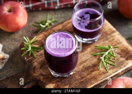 Violetter Kohlsaft mit frischen Äpfeln auf einem hölzernen Schneidebrett Stockfoto