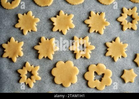 Verschiedene Formen aus Teig auf einem Blatt Backpapier - Zubereitung von selbstgemachten Linzer Weihnachtskeksen Stockfoto