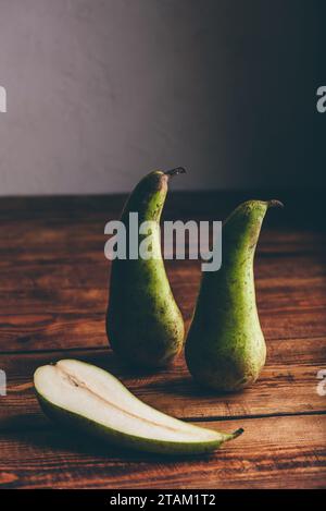 Stille Leben mit zwei ganzen Birnen und einer Hälfte auf Holzfläche Stockfoto