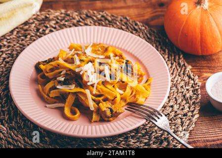 Fettuccine Pasta mit Kürbissauce und Pilzen garniert mit geriebenem Parmesan-Käse Stockfoto
