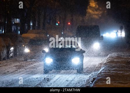 München, Deutschland. Dezember 2023. Autos fahren über eine schneebedeckte Straße. Quelle: Sven Hoppe/dpa/Alamy Live News Stockfoto