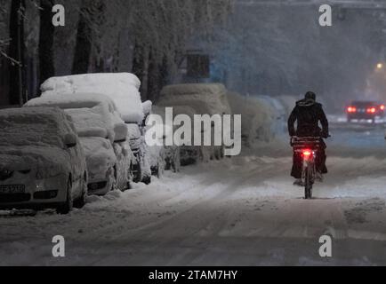 München, Deutschland. Dezember 2023. Ein Mann fährt mit dem Fahrrad über eine schneebedeckte Straße. Quelle: Sven Hoppe/dpa/Alamy Live News Stockfoto