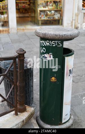 Zeichen des Übertourismus über Venedig und gute Manieren – Touristen gehen nach Hause, Graffiti auf einem grünen Abfalleimer an einer beliebten Brücke und Geschäften gemalt Stockfoto