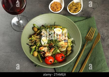 Leckeres Gericht mit Estragon, Salatdressings und einem Glas Wein, serviert auf grauem Tisch, über der Aussicht Stockfoto