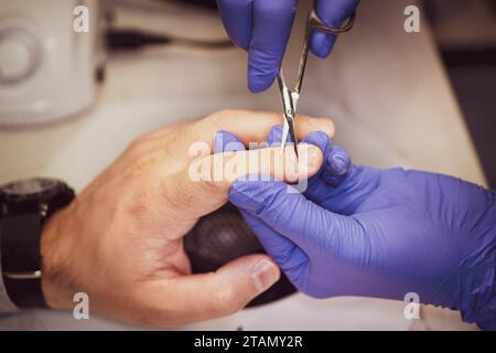 Der Mann für Verfahren in Maniküre Salon. Wellness, manicuring, Entfernen der Nagelhaut Schere. Schönen männlichen Händen. Stockfoto