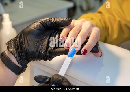 Frau im Nagelstudio wählt nagellackfarbe. gelpolitur. nagellack in verschiedenen Farben. Stockfoto