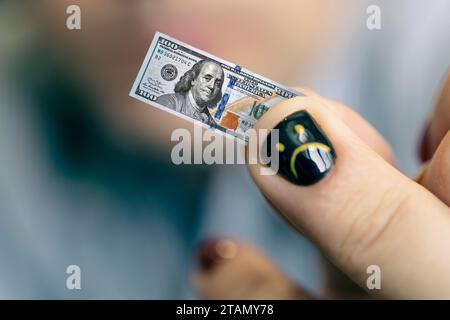 Ein junger Geschäftsmann hält eine kleine Rechnung in der Hand als Symbol für sinkendes Einkommen. Kleines Gehaltskonzept. Ein trauriges, lächelndes Gesicht ist auf den Nagel gezeichnet. Stockfoto