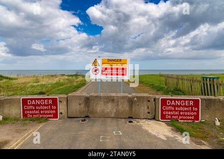 Warnschilder auf der gesperrten Straße zur Küste, die durch Erosion zerstört wurde, zu sehen in Aldbrough, East Riding of Yorkshire, England, Großbritannien Stockfoto