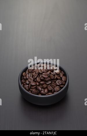 Dunkel geröstete Kaffeebohnen in einer kleinen schwarzen Keramikschale. Stockfoto