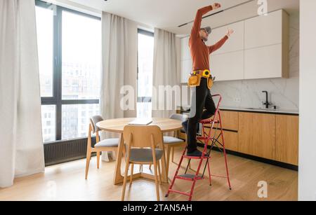 Elektriker repariert Deckenventilator mit Lampen im Innenbereich. Platz für Text. Stockfoto