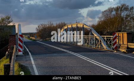 Abendlicht fällt auf die Balken einer alten Stahlbrücke über den Fluss Vidå in der Nähe der Stadt Tønder in Süddänemark Stockfoto