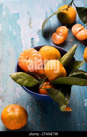 Frische saftige Mandarinen in einer blauen Keramikschale auf hölzernem Hintergrund. Stockfoto