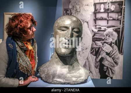 Dorset, England, Großbritannien. Dezember 2023. Tribute III, Foto der Künstlerin bei der Arbeit (rechts), dreißig Jahre nach ihrem Tod, die erste Ausstellung, die Elisabeth Frinks Zeit in Dorset gewidmet ist und über 80 Skulpturen, Zeichnungen und Drucke im Dorset Museum zeigt, einschließlich der Arbeitspflaster, die die finalen Bronzeskulpturen informierten, die nie öffentlich ausgestellt wurden vom 2. Dezember 2023 bis 21. April 2024.Paul Quezada-Neiman/Alamy Live News Credit: Paul Quezada-Neiman/Alamy Live News Stockfoto