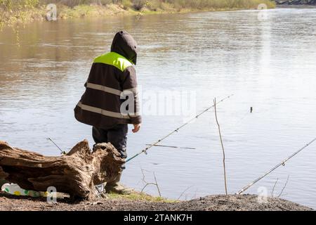 Ein Angler fängt Fische mit mehreren Angelruten am Ufer des Flusses Stockfoto