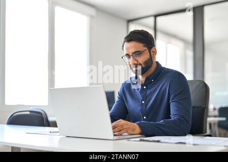 Beschäftigter indischer Geschäftsmann Firmenmitarbeiter, der Laptop benutzt und im Büro arbeitet. Stockfoto