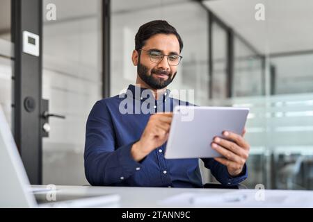 Beschäftigter indischer Geschäftsmann, der ein digitales Tablet verwendet und im Büro arbeitet. Stockfoto