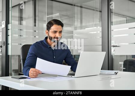 Beschäftigter indischer Geschäftsmann, Analyst, der mit Computer Finanzberichte hält. Stockfoto