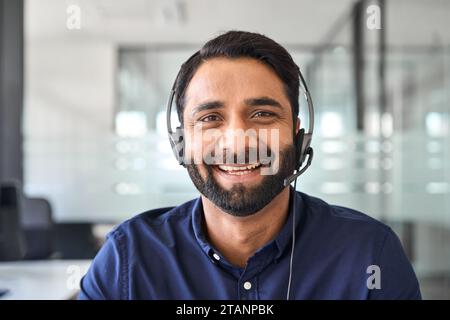 Glücklicher indischer Callcenter-Agent, der im Büro ein Headset trägt. Hochformat. Stockfoto