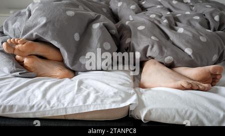 Nahaufnahme der Füße eines Paares, die auf dem Bett liegen und sich von einander abwenden. Familienkonflikt und Streit, schlechte Beziehungen Stockfoto