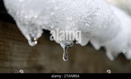 Nahaufnahme von Wassertröpfchen, die von Eiszapfen auf einem Dach kaskadieren. Die Schönheit der Natur und die Ankunft des Frühlings Stockfoto