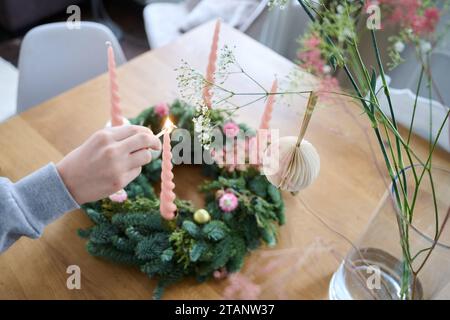 Berlin, Deutschland. Dezember 2023. Ein Junge zündet die erste Kerze an einem dekorierten Adventskranz an. Annette Riedl/dpa/Alamy Live News Stockfoto